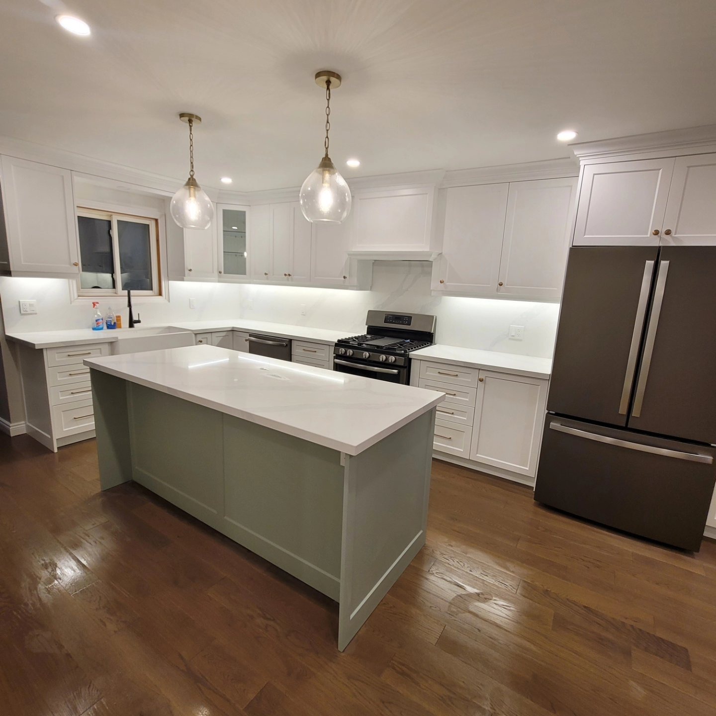 Finished kitchen with white cabinets and sage-green island